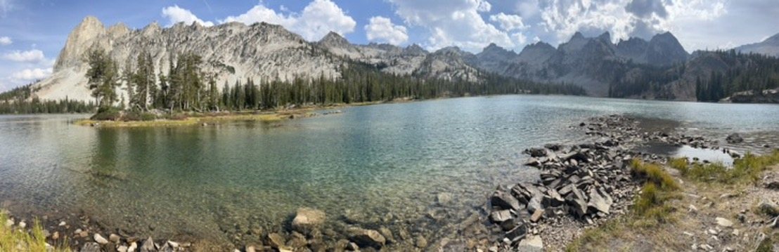 Wide view of a clear mountain lake beneath jagged granite peaks